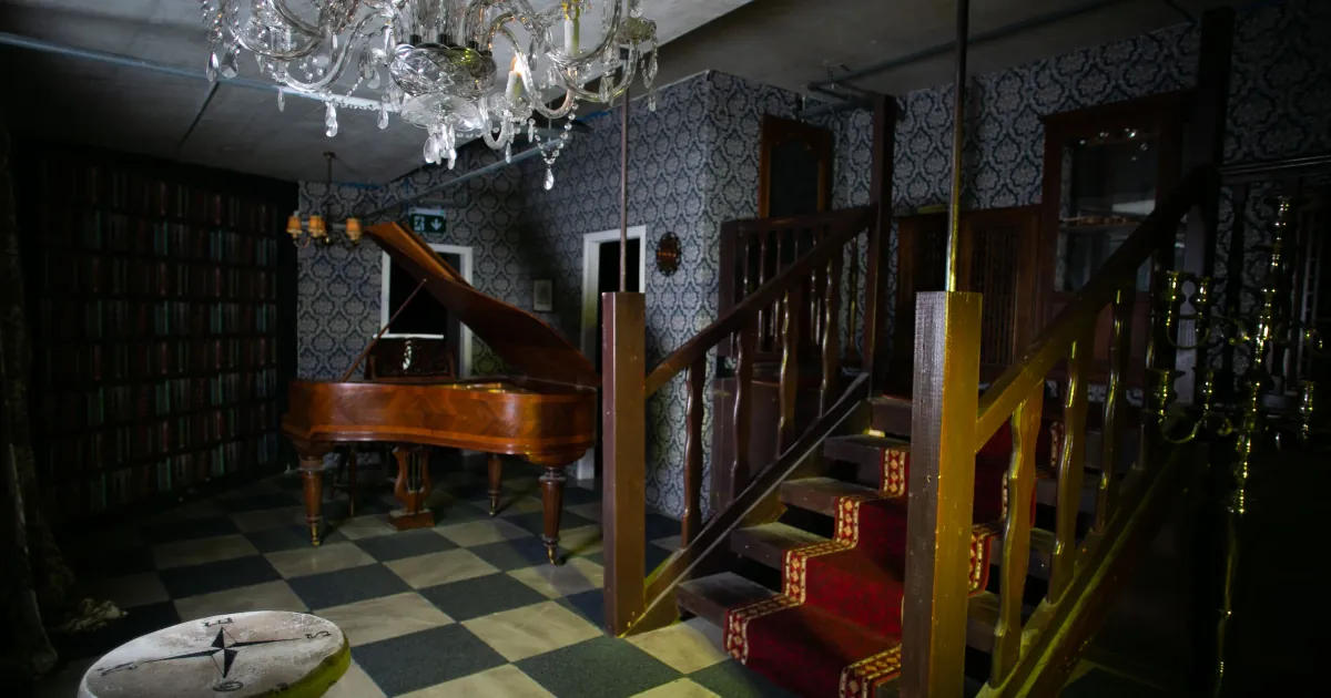 Le grand salon du Secret du Manoir, la salle LaseRed de Lausanne : piano à queue, lustre en cristal et escalier